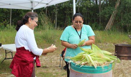 Two women processing corn