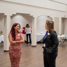 Two women standing and chatting in a conference room