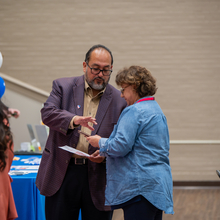 A man showing a woman how to scan a paper with her phone