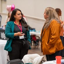 Two women standing and chatting in a conference room