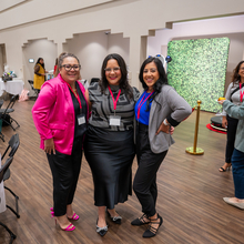 Tres mujeres posando para la cámara en una sala de conferencia