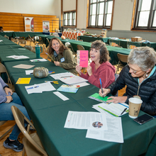 Group of 4 women sit at a table conversing and smiling