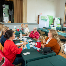 Several women sitting and conversing around a table. 