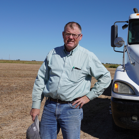 Man standing in field in front of grain truck