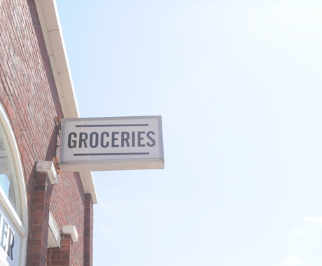 Mostly blue sky, at the left of the picture is a brick building with a white sign. In black lettering it says "groceries"