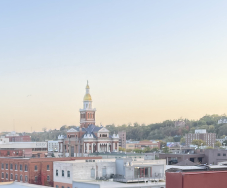 A large government building with a gold dome on top, with a yellow sunset in the sky background