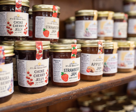 Jars of jelly lined up on a shelf, stacked 2 jars high and about 3 jars deep