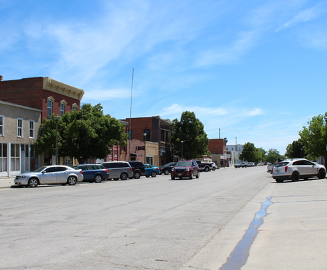 Small town main street with brick two-story buildings on each side and cars parked on either side.