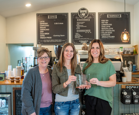 Tres dones blanques en una cafeteria amb un premi