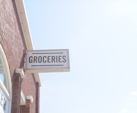 White sign saying groceries written in black on the side of a building.