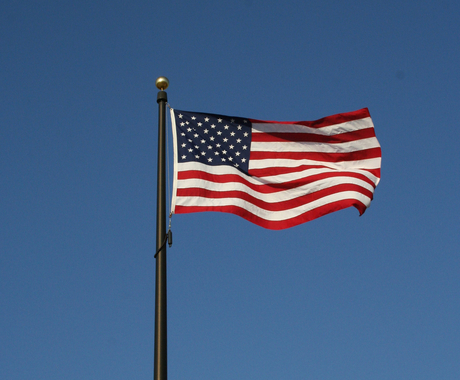 Bandera nord-americana vuela amb el viento en un cielo azul oscuro sin nuves