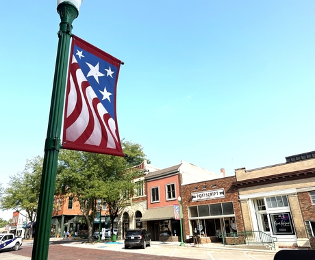 Bandera de disseny de bandera americana al pal de llum amb edificis al fons
