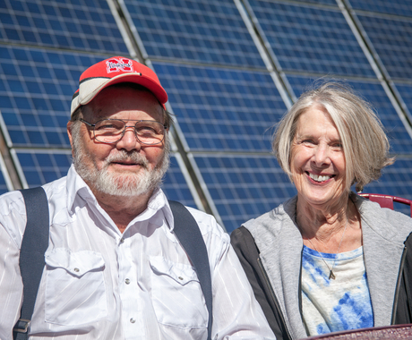 home i dona posant per a una foto davant del panell solar