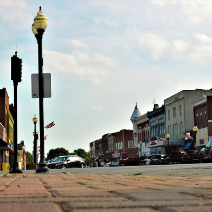 Community Main Street with buildings, light poles with American flats attached, and cars on both sides