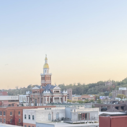 A large government building with a gold dome on top, with a yellow sunset in the sky background