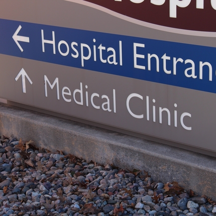 Rètol gris amb l'entrada de l'hospital en blanc sobre fons blau i Clínica mèdica en text blanc sobre fons gris.