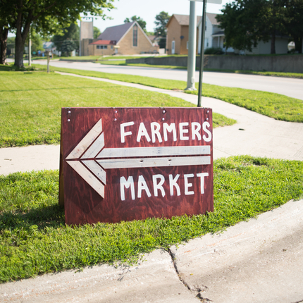 yard sign that says farmers market with a large arrow