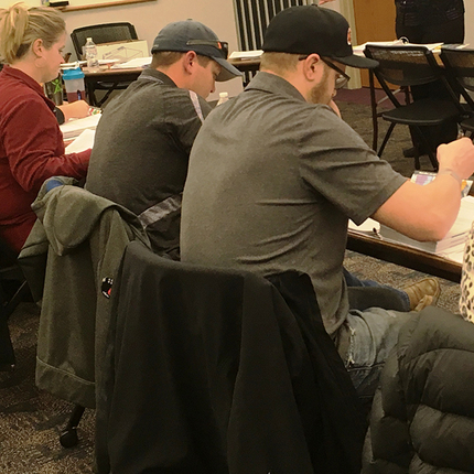 group of people sitting at table, writing