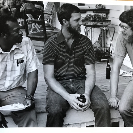 Tres homes asseguts a la vora d'un escenari. Foto dels anys 1970.
