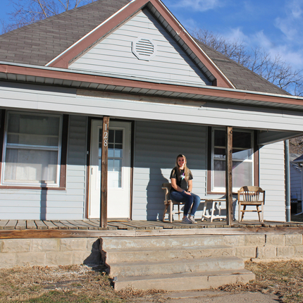 Woman sitting on front porch of house