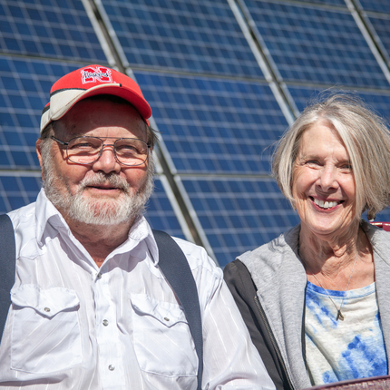 home i dona posant per a una foto davant del panell solar