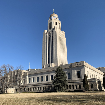 Edifici del Capitoli de l'estat de Nebraska: un edifici pla de granit de dos pisos amb una agulla que s'aixeca pel mig, amb una cúpula de bronze a la part superior