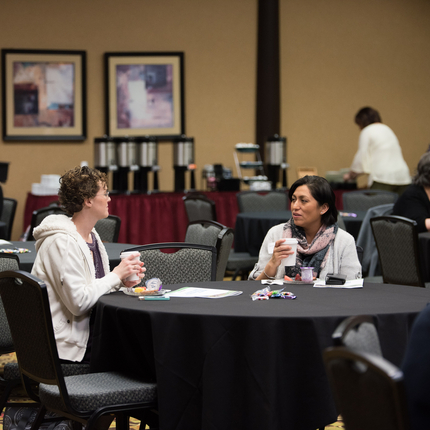 two women sitting at a table, talking