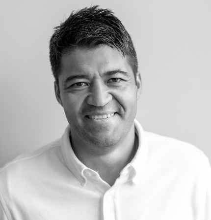 Latino man with dark short hair, smiling at camera, wearing a white collared shirt