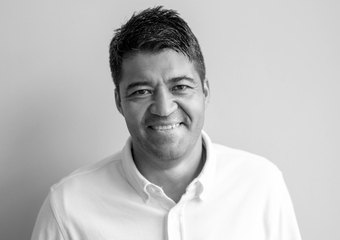 Latino man with dark short hair, smiling at camera, wearing a white collared shirt